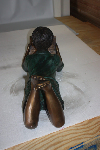 boy laying reading book bronze Statue -  Size: 24"L x 10"W x 11"H. 