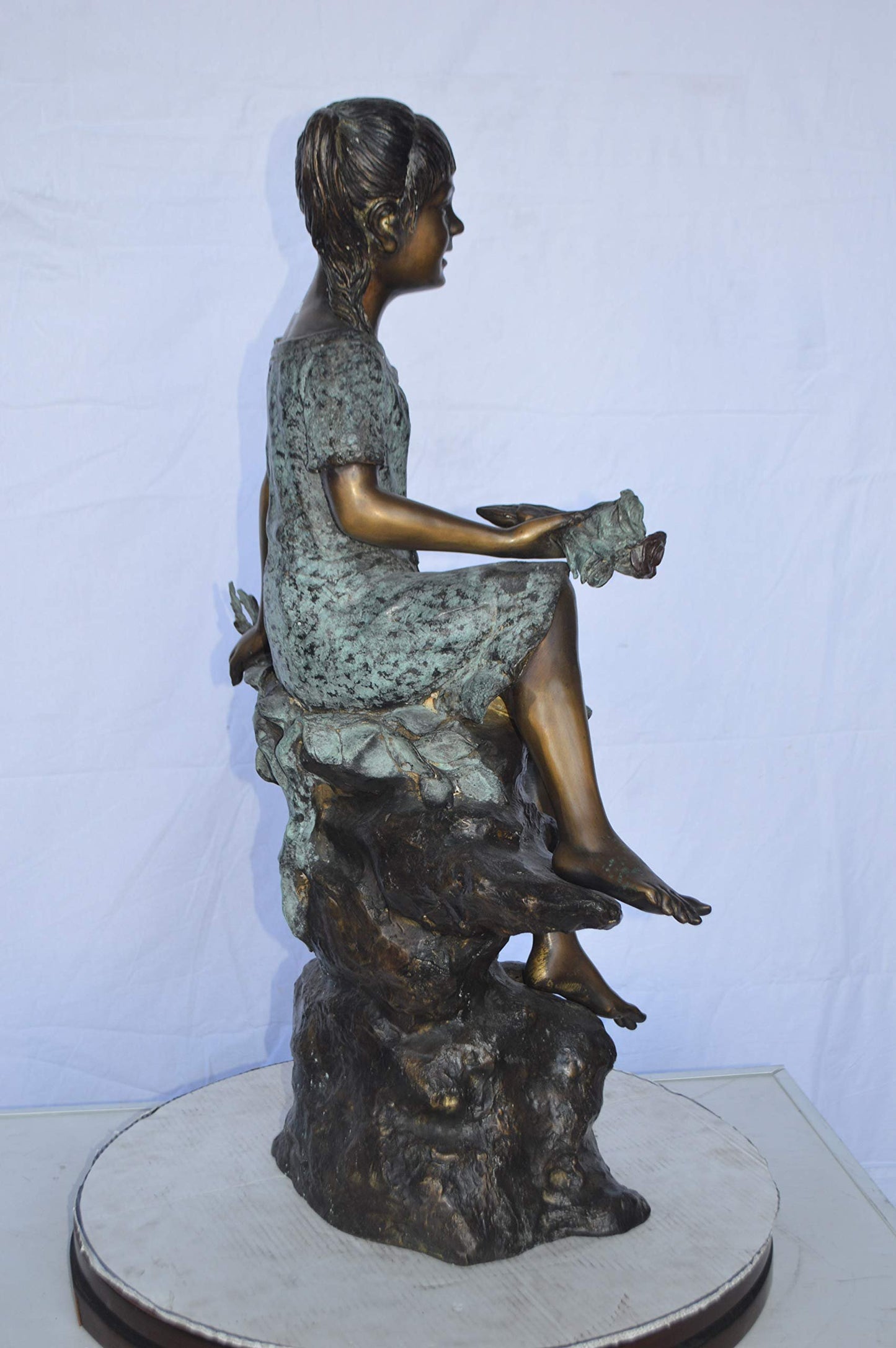 Girl on Tree  Trunk Holding Flowers Bronze Statue -  Size: 26"L x 11"W x 36"H.