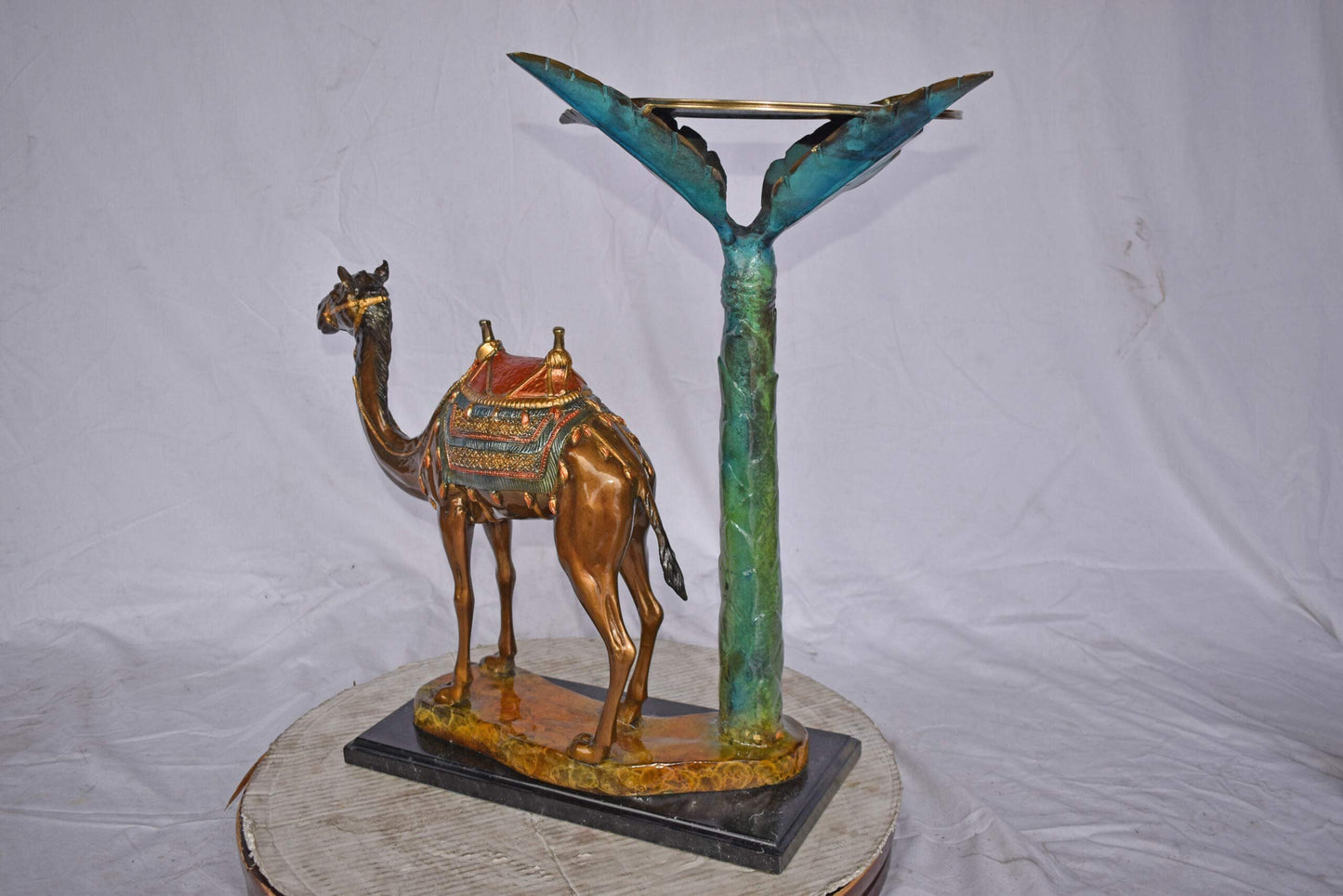 Camel Standing Under A Palm Tree Bronze Statue - Size: 20"L x 29"W x 25"H.