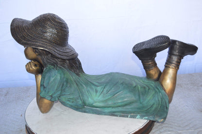 Girl Wearing A Hat Lying on Stomach Bronze Statue -  Size: 33"L x 17"W x 17"H.