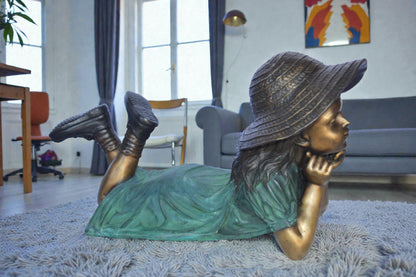 Girl Wearing A Hat Lying on Stomach Bronze Statue -  Size: 33"L x 17"W x 17"H.