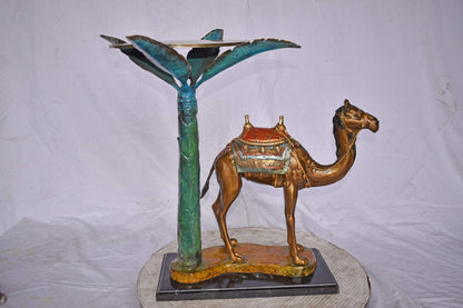 Camel Standing Under A Palm Tree Bronze Statue - Size: 20"L x 29"W x 25"H.