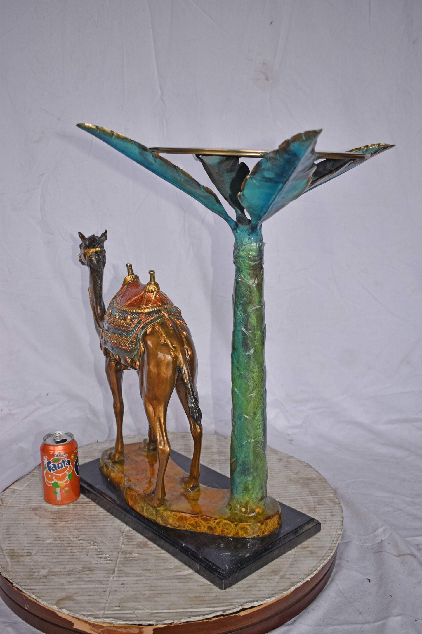 Camel Standing Under A Palm Tree Bronze Statue - Size: 20"L x 29"W x 25"H.