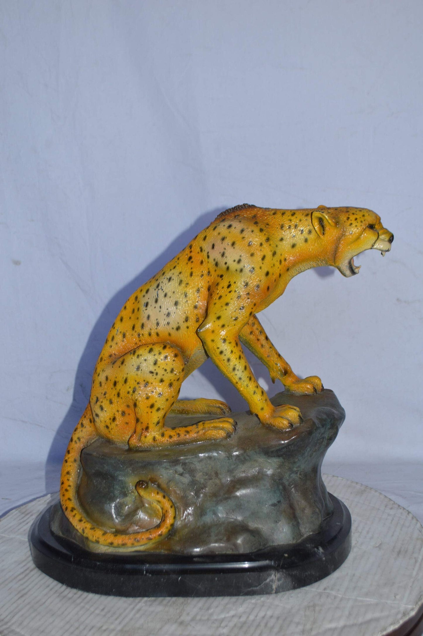 Cheetah sitting on a rock growling bronze statue - Size: 18"L x 12"W x 18"H.