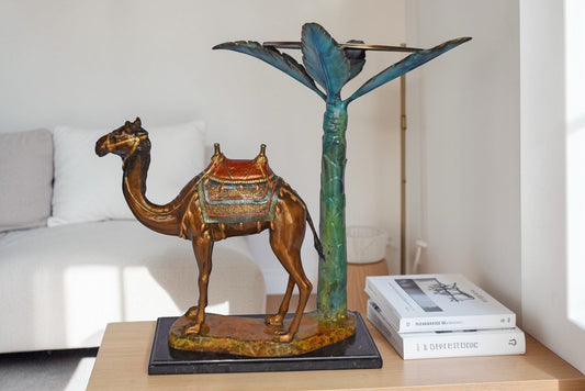 Camel Standing Under A Palm Tree Bronze Statue - Size: 20"L x 29"W x 25"H.