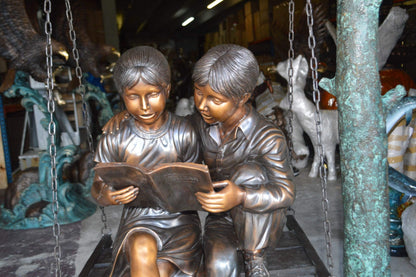 NIFAO Kids on Swing Set Reading a Book Bronze Statue – Rhian Handcrafted Sculpture with Joyful Detail for Gardens, Lawns, or Playful Outdoor Spaces – 50" L x 40" W x 70" H