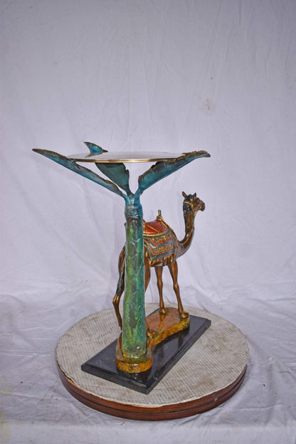 Camel Standing Under A Palm Tree Bronze Statue - Size: 20"L x 29"W x 25"H.
