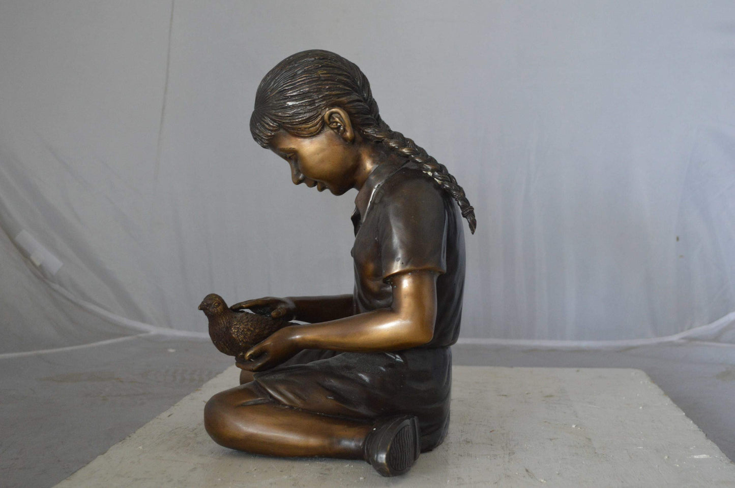 Young seated girl with bird bronze statue - Size: 12"L x 9"W x 14"H.