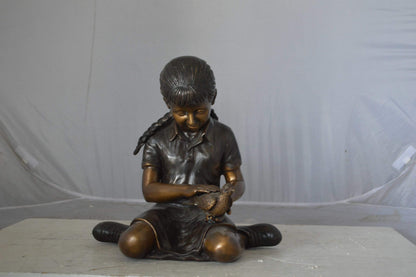 Young seated girl with bird bronze statue - Size: 12"L x 9"W x 14"H.