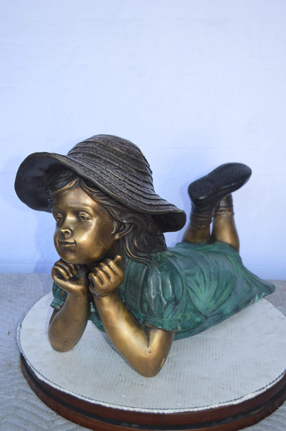 Girl Wearing A Hat Lying on Stomach Bronze Statue -  Size: 33"L x 17"W x 17"H.