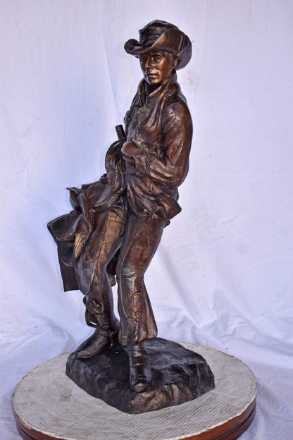Cowboy Holding His Saddle Bronze Statue - Size: 20"L x 14"W x 35"H.