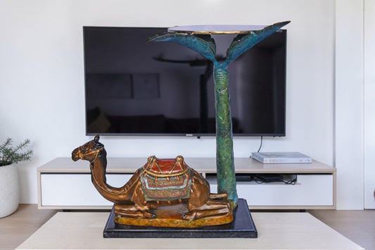 Camel Sitting Under A Palm Tree Bronze Statue - Size: 17"L x 27"W x 23"H.