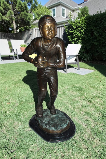 Boy playing football Bronze Statue -  Size: 10"L x 8"W x 20"H.