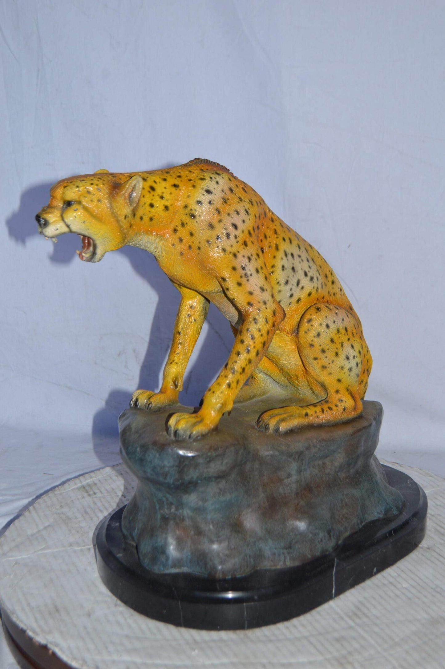 Cheetah sitting on a rock growling bronze statue - Size: 18"L x 12"W x 18"H.