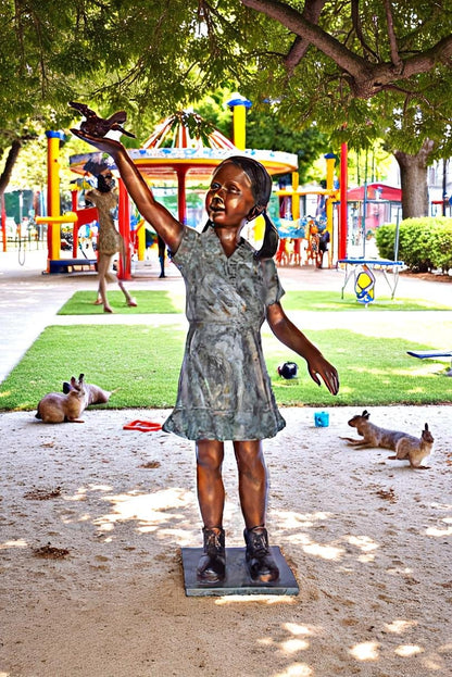 Young Girl Holding a Bird Outside at The Park - Size: 21"L x 11"W x 49"H.
