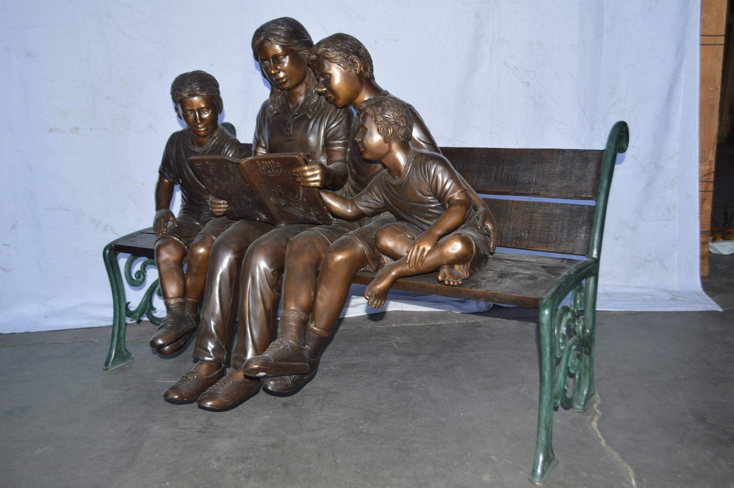 Mom and boys reading stories on bench bronze statue - Size: 53"L x 33"W x 39"H.