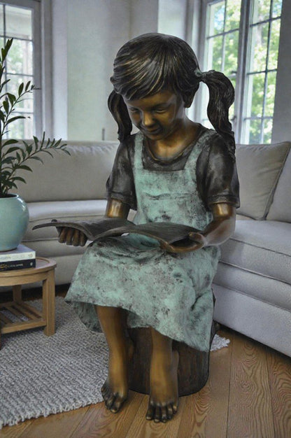 Young girl sitting and reading book bronze statue -  Size: 16"L x 12"W x 27"H.