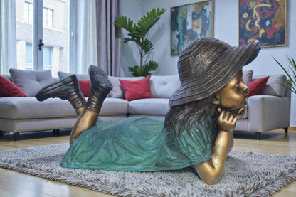 Girl Wearing A Hat Lying on Stomach Bronze Statue -  Size: 33"L x 17"W x 17"H.