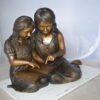 Two Girls Reading a Book Bronze Statue -  Size: 33"L x 21"W x 23"H.