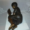 Girl laying reading a book Bronze Statue -  Size: 36"L x 17"W x 18"H.