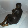 Girl laying reading a book Bronze Statue -  Size: 36"L x 17"W x 18"H.