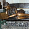 Girl laying on a bench reading a book Bronze Statue -  Size: 27"L x 39"W x 32"H