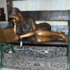 Girl laying on a bench reading a book Bronze Statue -  Size: 27"L x 39"W x 32"H