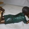 boy laying reading book bronze Statue -  Size: 24"L x 10"W x 11"H.