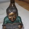 boy laying reading book bronze Statue -  Size: 24"L x 10"W x 11"H.